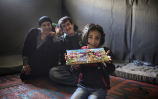 Syrian refugee Solaf, excitedly showcases her completed puzzle in a tent at Azraq refugee camp. Her father Ahmad, 49, and mother Ruwaidah, 44, decided to flee Syria with their children in 2013. © UNHCR / A. SAKKAB