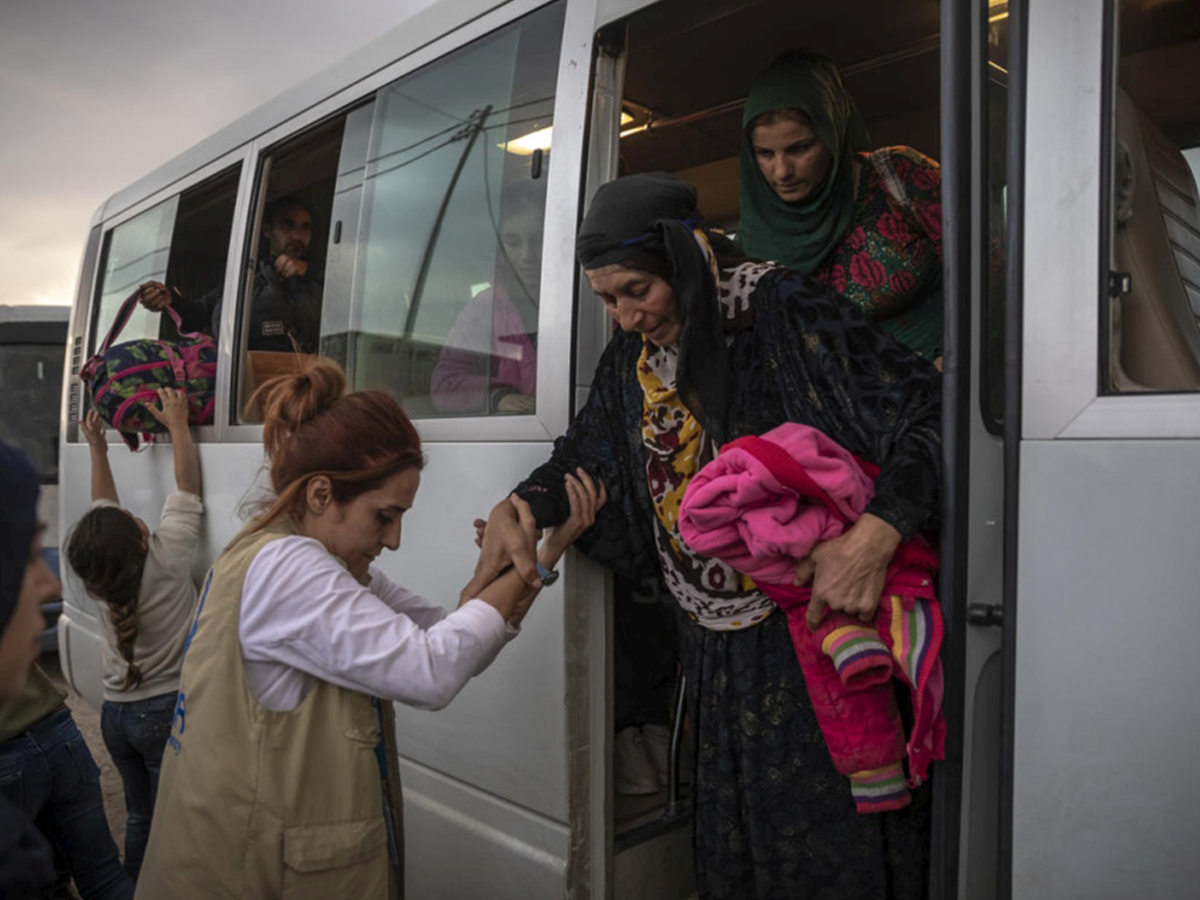 People in Syria board a bus