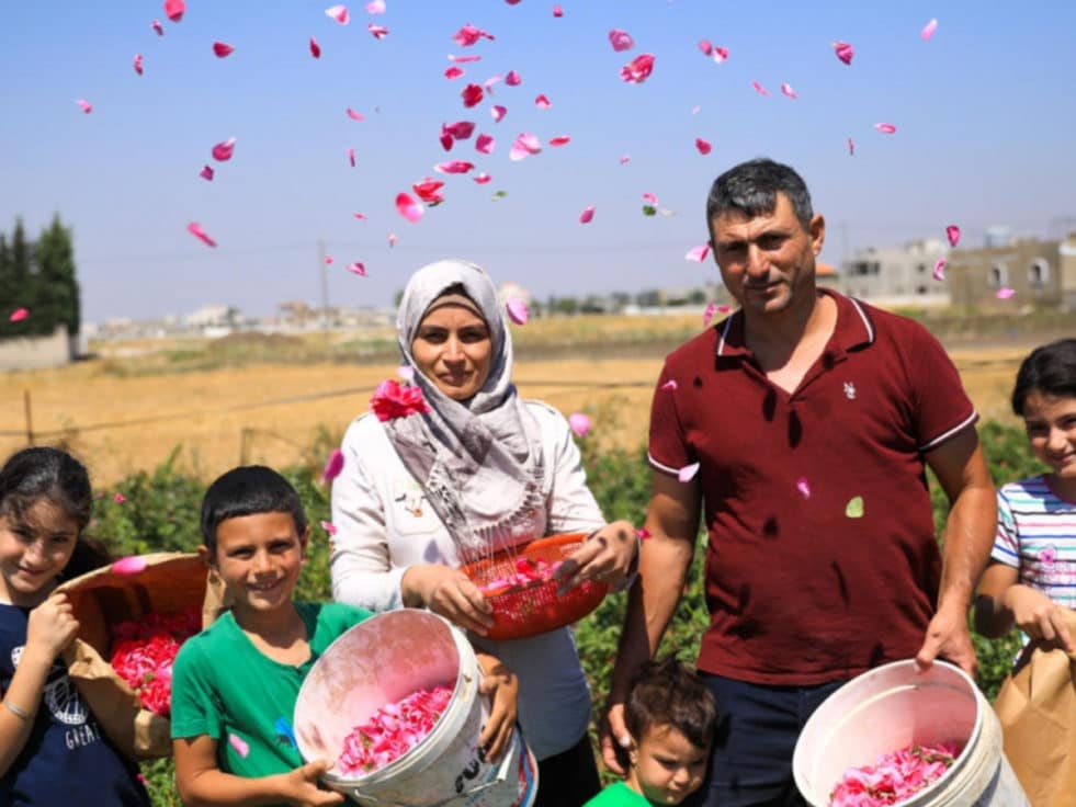 famille de réfugiés syriens devant une ferme rose