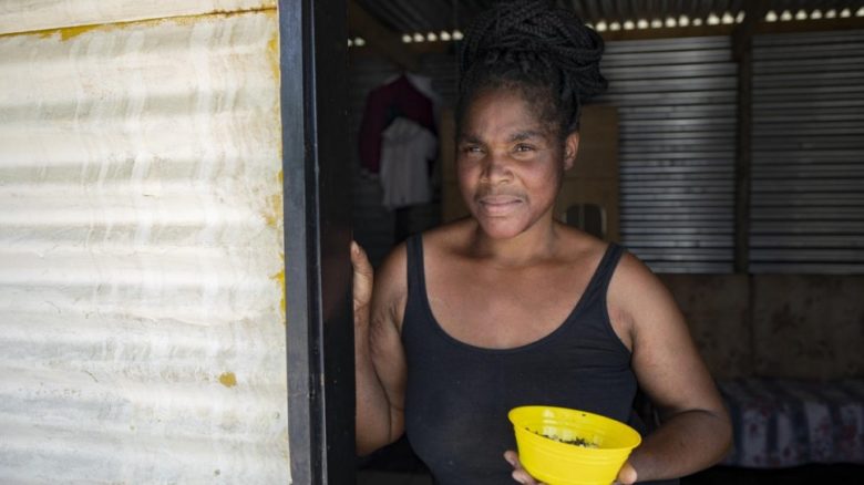 Mpho Modise stands by the entrance of her small tin shack in Brits, South Africa. She lacks identity papers as her birth was never registered.