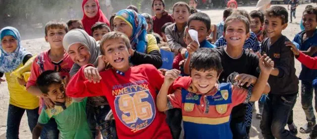 Group of kids smiling and huddling in front of the camera