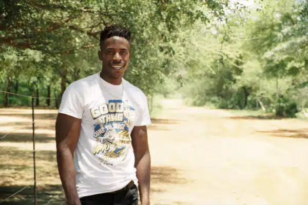 A man smiles standing in front of a path with trees