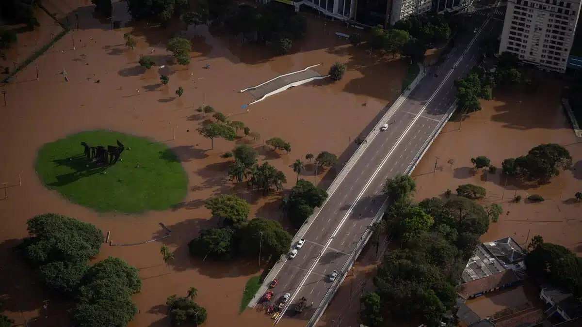 Vue aérienne d'une ville subissant de graves inondations. L'image montre un pont enjambant les eaux de crue, sur lequel se trouvent quelques véhicules.