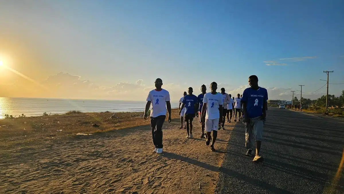 Group of people walking on a road in a deserted area. They are all wearing the same shirt.