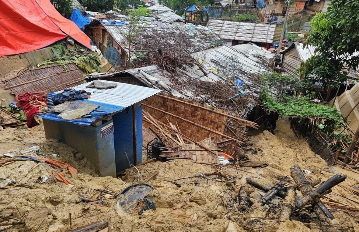 A few houses surrounded by debris have been destroyed. Some trees have been uprooted and their branches are scattered around.