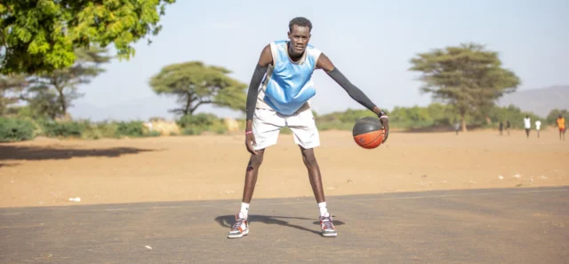 Un homme en tenue de sport joue avec un ballon de basket.