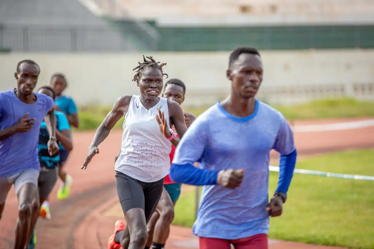 Six people are running on a track field.