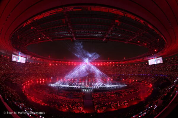 A large circular stadium lit in the colour red with an intersection of bright strobe lights in the center.