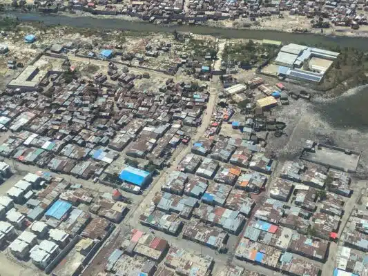 Vue aérienne d'une petite ville avec des chemins de terre. Les bâtiments sont construits avec des morceaux de ferraille non assortis.