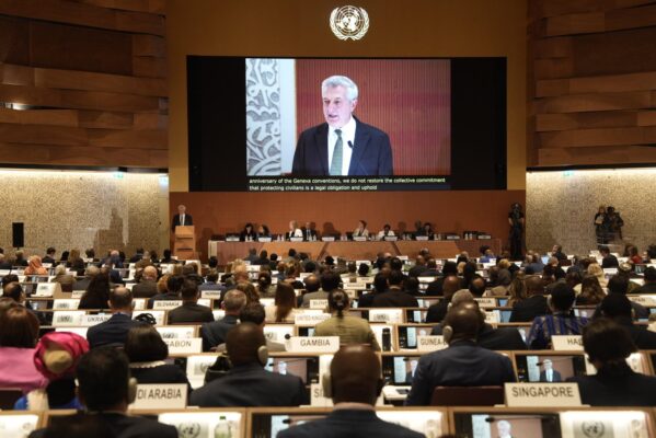 Une salle remplie de représentants de pays en tenue officielle se dirige vers l'avant de la salle où un écran affiche l'orateur, Filippo Grandi, qui s'exprime à l'avant de la salle.