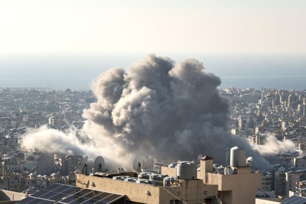 A cloud of smoke is pictured from an aerial view, looming over several lower industrial buildings and homes.