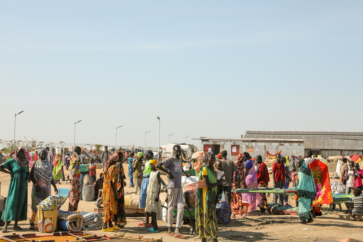  réfugiés, dont beaucoup portent leurs affaires, se tient sur un terrain poussiéreux dans le centre de transit de Renk pour les réfugiés arrivant au Sud-Soudan en provenance du Soudan.